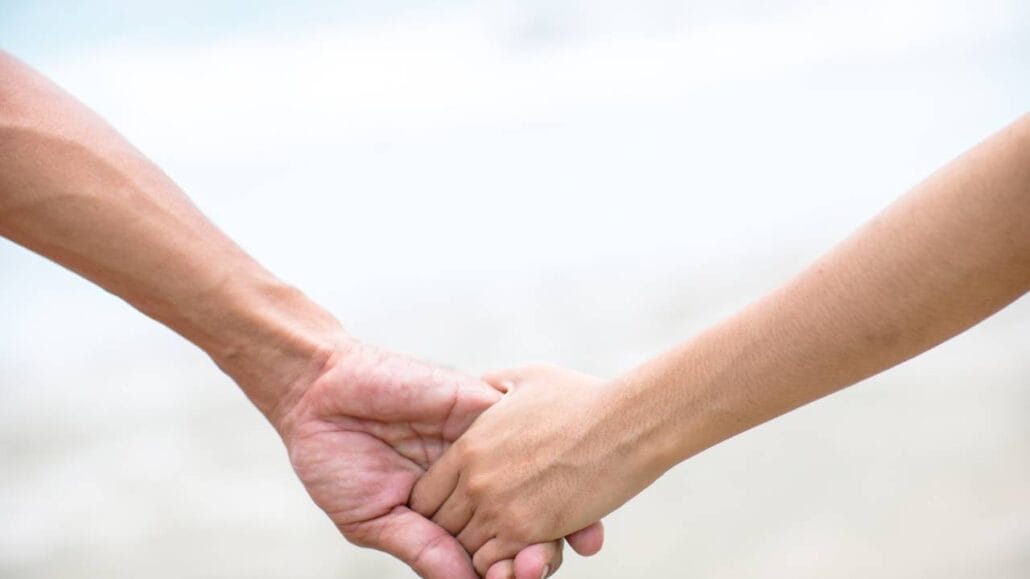 Homem e mulher com as mãos dadas.
