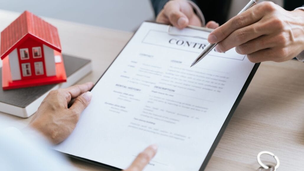 pessoa apontando um documento de itcmd com uma casa vermelha ao lado