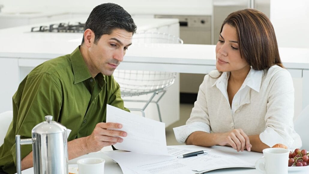 casal na cozinha assinando documento para pacto antenupcial