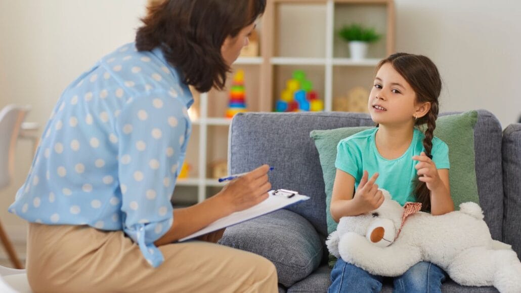 criança com ursinho no colo em sessão de terapia