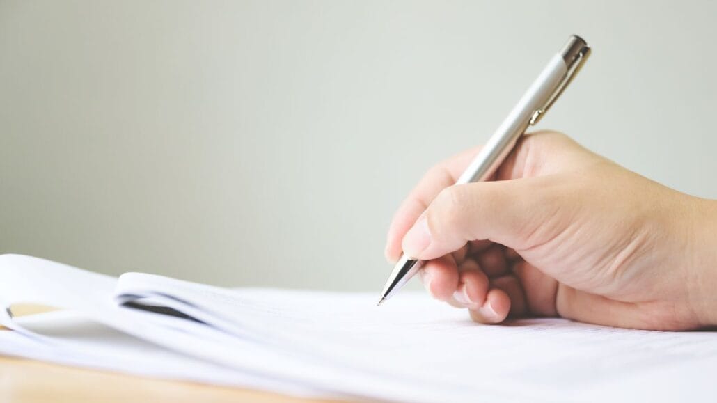 mão de uma pessoa assinando o testando