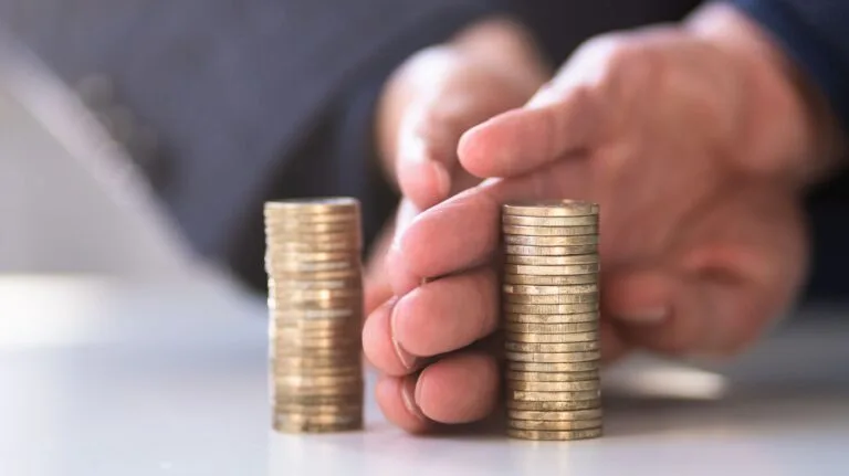 mãos separando dois aumontoados de moedas para ilustrar um post sobre regime de separação total de bens